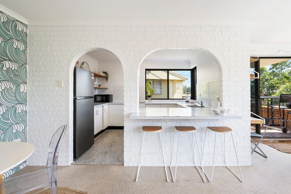Modern kitchen with microwave, oven, dishwasher, fridge, island, and utensils.