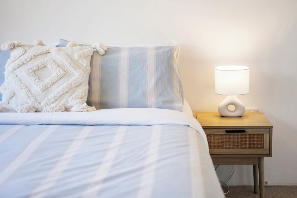 Queen bed bedroom with quality linens, natural light, fan, and window view.