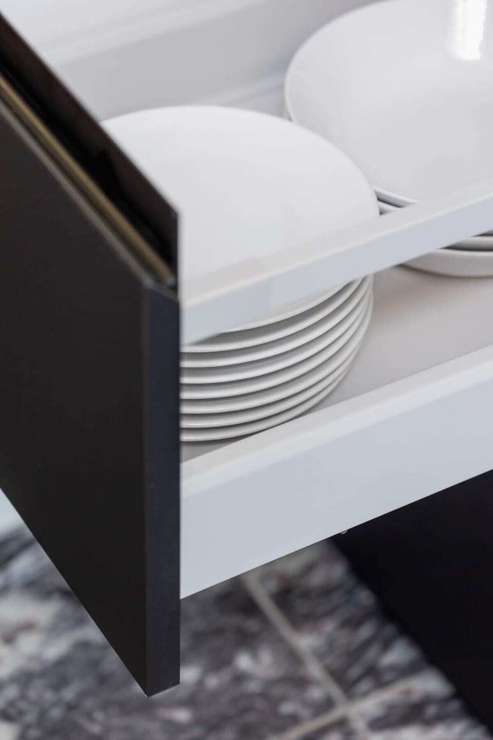 A pull-out drawer revealing neatly arranged dishes and utensils for guest use.
