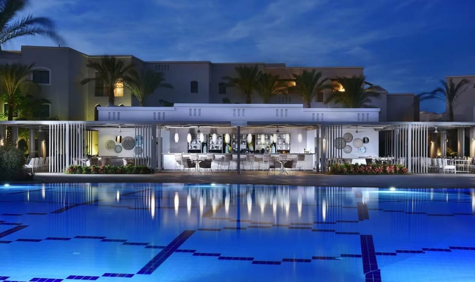 Sip cocktails poolside while warm lights shimmer across the water.
