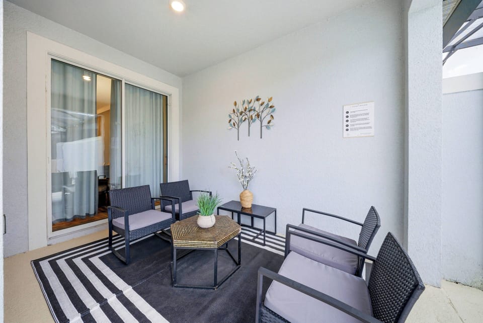 Experience the charm of this terrace with a chic black-and-white striped rug and four modern wicker chairs around a stylish coffee table. Large glass doors let in warm light, creating a perfect spot for relaxation or entertaining.
