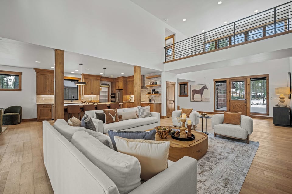 Relax in your spacious open-concept living area with soaring ceilings, warm wood accents, and plush seating perfect for gathering.