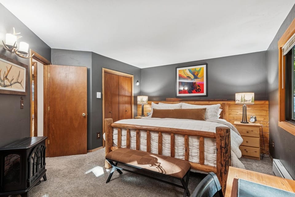 Unwind in your cozy bedroom featuring rustic wood furniture, plush bedding, and a warming fireplace for ultimate mountain retreat comfort.