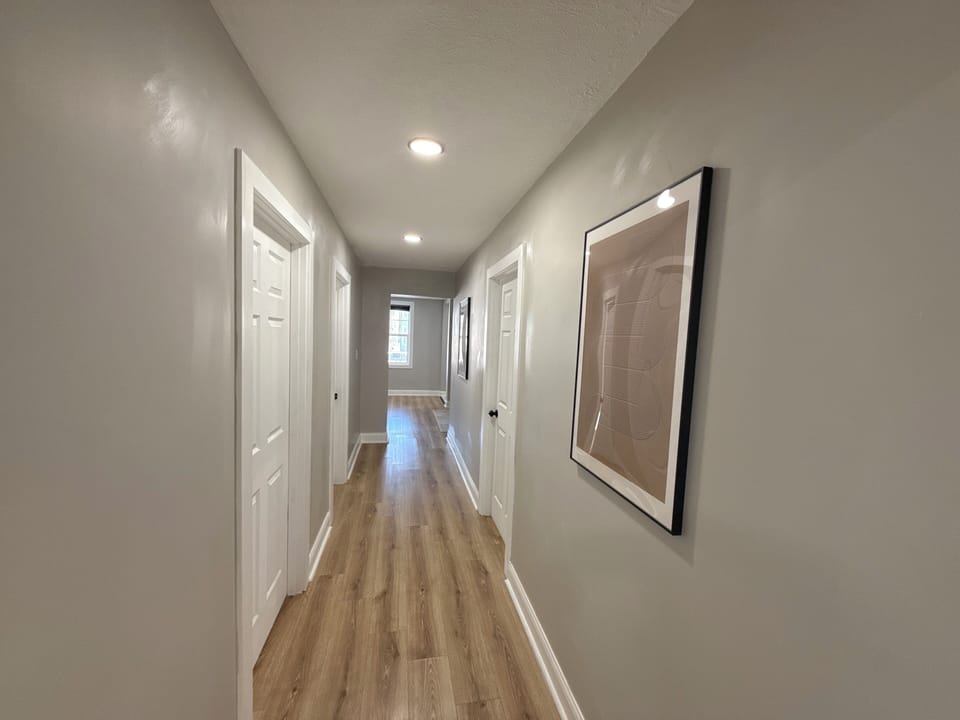Clean, well-lit hallway connecting bedrooms and common areas. Neutral tones and recessed lighting create a calm, modern flow throughout the home.