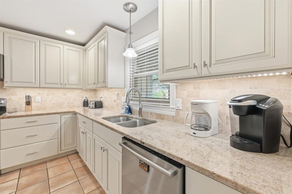 Modern kitchen with granite counters, stainless appliances, and a breakfast bar for three.