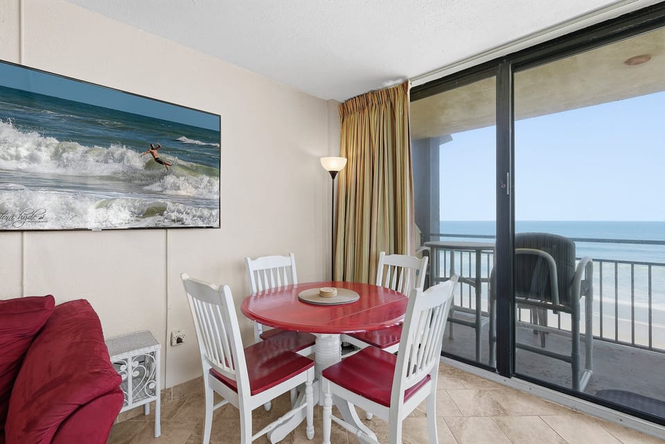Enjoy meals with breathtaking ocean views in this bright dining space featuring balcony access and coastal charm. Perfect for morning coffee or sunset dinners, this beach stay vacation rental puts you just steps from the sand.