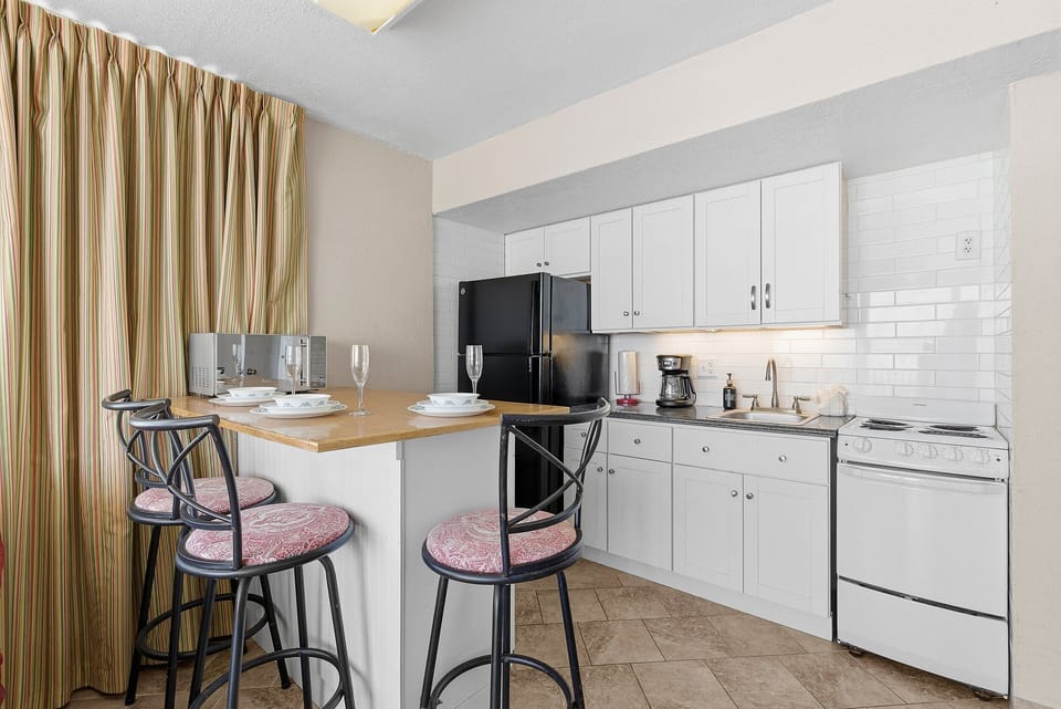 Enjoy the ease of this bright kitchenette featuring a breakfast bar, full-size appliances, and everything needed for your beach stay. Perfect for morning coffee or casual meals during your relaxing seaside vacation rental getaway.