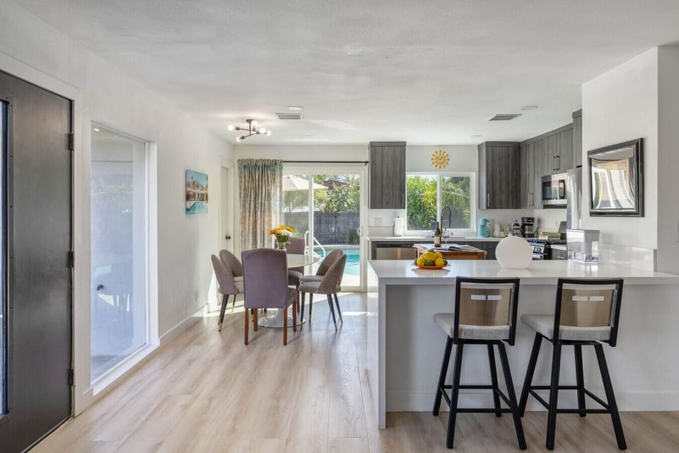 A modern, airy layout featuring a sleek kitchen with stainless steel appliances, a spacious island with bar seating, and seamless flow into the living space.