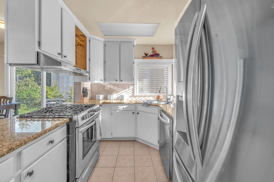Your fully equipped kitchen features granite counters, stainless steel appliances, and a bright window overlooking greenery—perfect for cooking memorable meals.