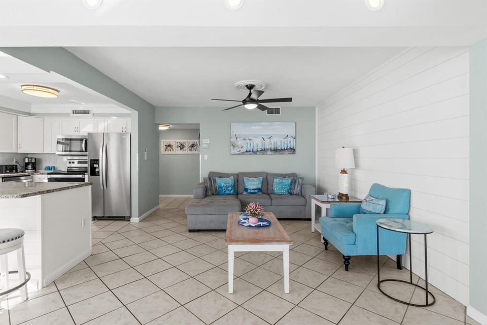 Relax in your coastal-inspired living room with comfortable seating and modern kitchen convenience.