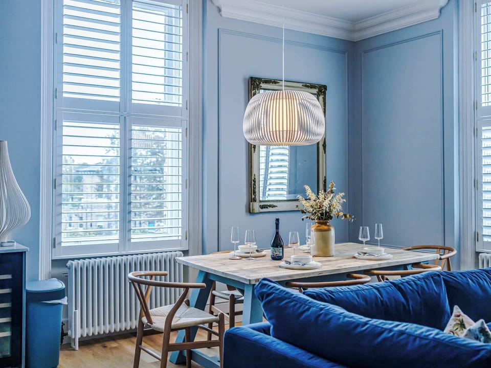 Bright and inviting living room with a navy sofa, large windows, and warm wood floors. Scandinavian-inspired décor blends modern style with comfort, creating a cozy space perfect for relaxing or entertaining in natural light.
