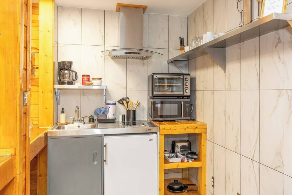 - Stainless sink station with coffee maker and cooking essentials   - Two appliance stack with convection oven and microwave   - Efficient cabin kitchen space with modern rustic style