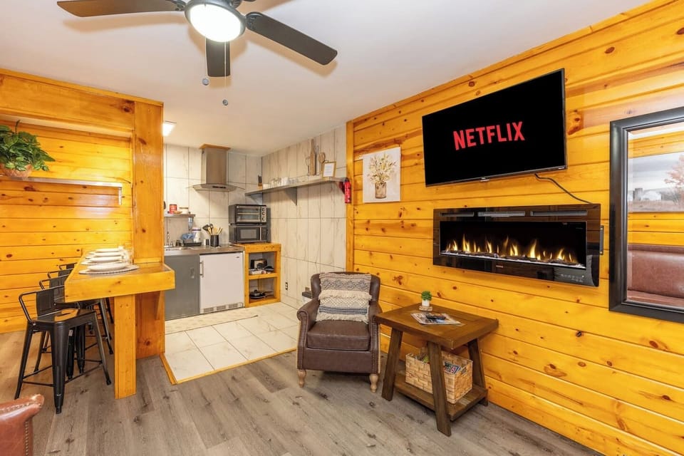 - Modern cabin lounge with electric fireplace and large smart TV - Open concept kitchenette, bar seating and leather accent chair - Romantic getaway rental with streaming, dining nook and warm decor