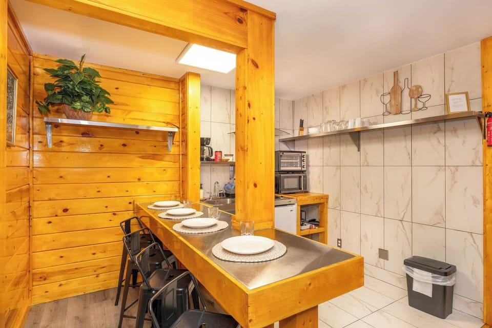 - Breakfast bar dining area with wood beams and metal stools - Cozy cabin kitchen setup with plates, glassware and coffee maker - Intimate getaway space with rustic charm and functional design