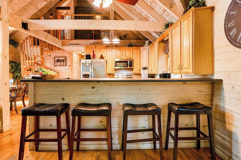 Rustic cabin kitchen with breakfast bar, loft views, and warm wood charm