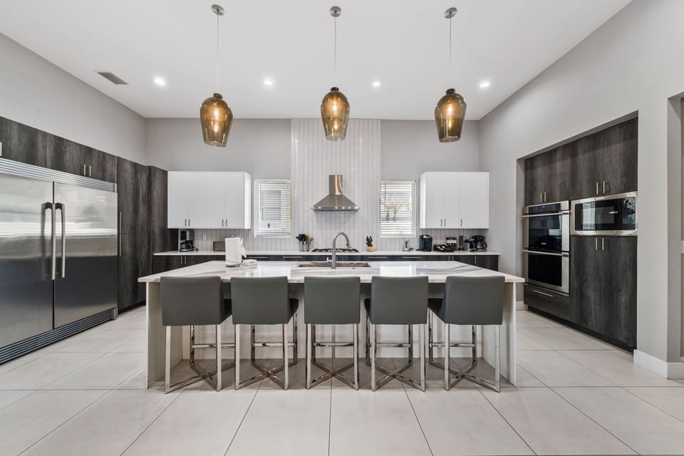 The kitchen has stainless steel appliances and a double door commercial refrigeratorThe breakfast bar has seating for up to 5 guests