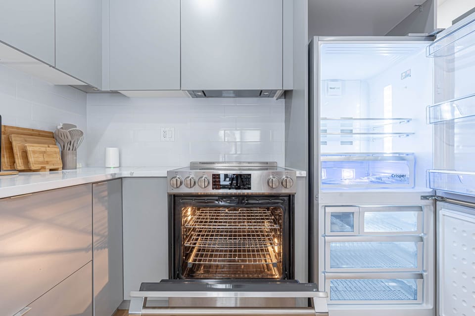 Kitchen with cabinets, an oven, and an open stainless steel refrigerator.