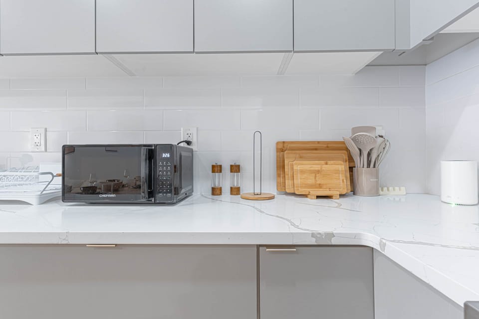 Kitchen counter with a microwave, cutting boards, and cabinets.S