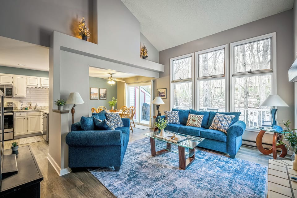 A bright, open living space with vaulted ceilings, forest views, and cozy seating—perfect for gathering after a day in the Poconos.