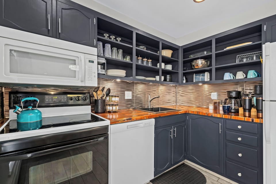Your fully equipped kitchen awaits with modern appliances, warm wood countertops, and everything you need to create memorable meals during your stay.