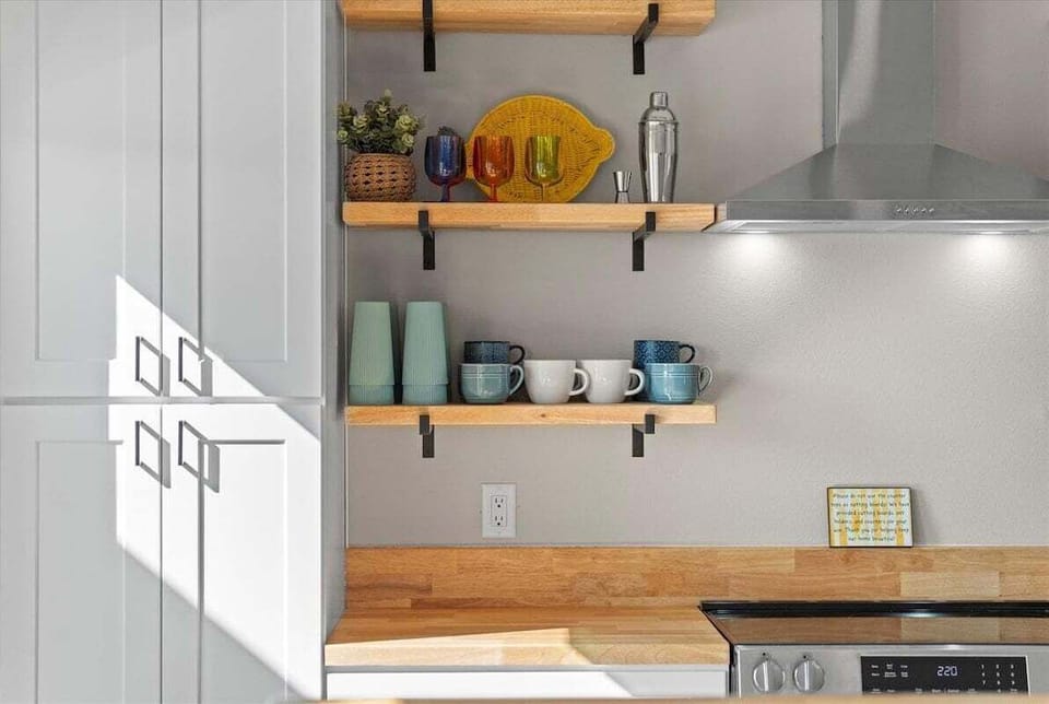 Coffee and beverage station with open shelving, countertop space, and stylish coastal-inspired kitchen decor.