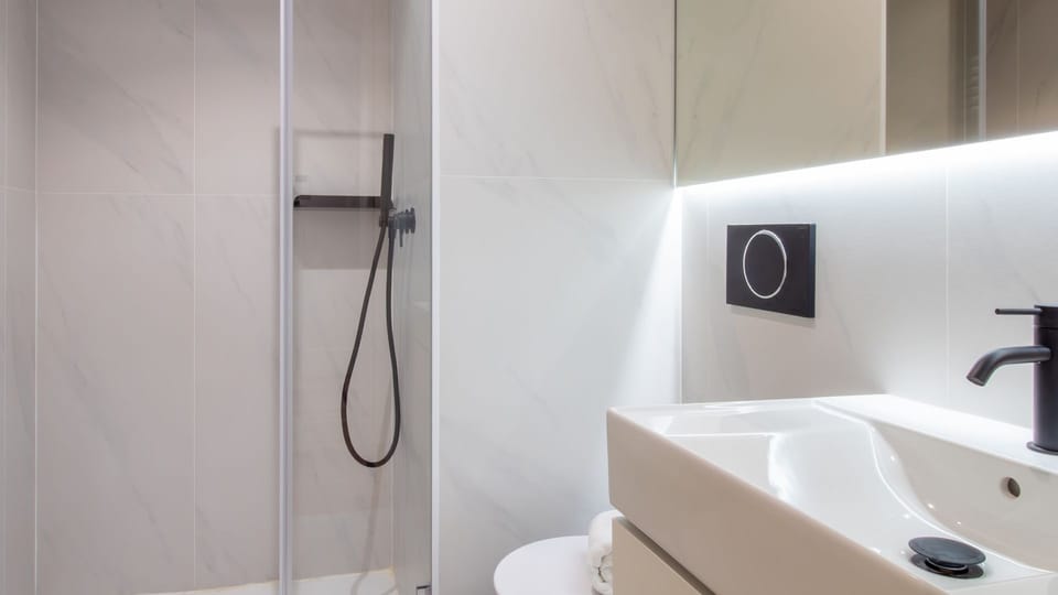 Sleek bathroom with walk-in shower, black matte fixtures, and warm lighting for a refined, spa-like atmosphere.
#ModernBathroom #RainfallShower #LuxuryFinishes #StayInStyle