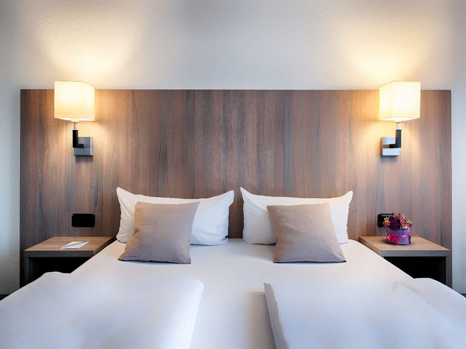 Sink into crisp linens beneath warm, calming bedside lighting.