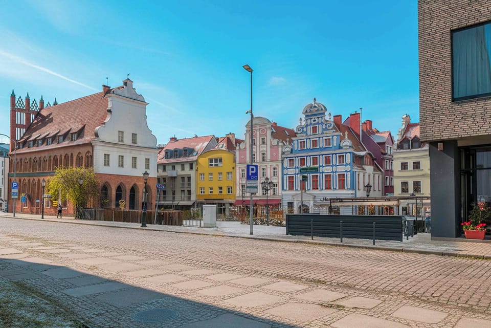 A colorful city square with historic buildings and open space. The scene feels lively and full of character.