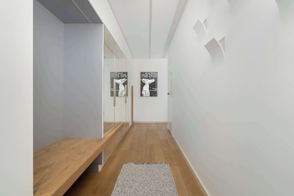 A minimalist hallway with light walls, wooden flooring, and simple decor that creates a welcoming entrance.
