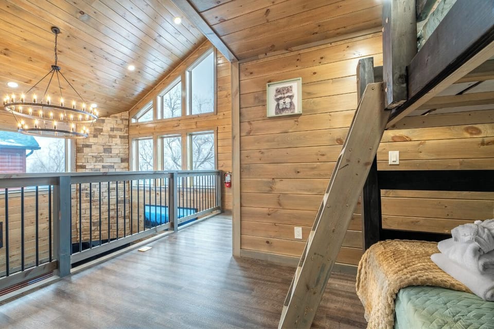 Cozy loft space with rustic wood beams and chandelier lighting creates your perfect retreat above the main living area.