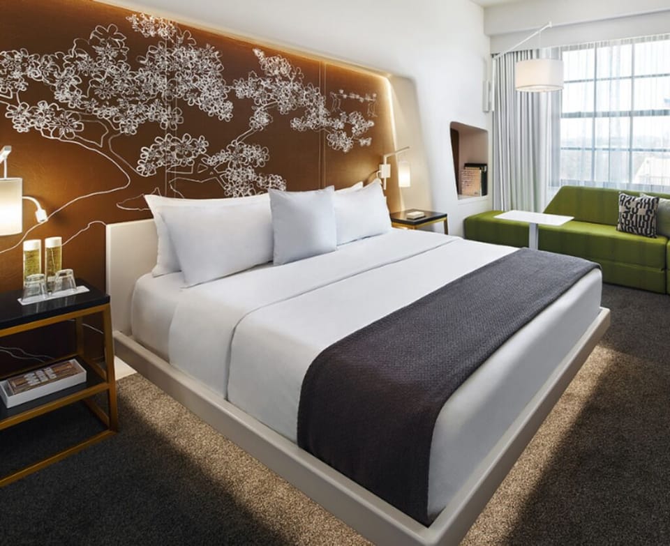 Unwind in crisp linens beneath a glowing, artful headboard.