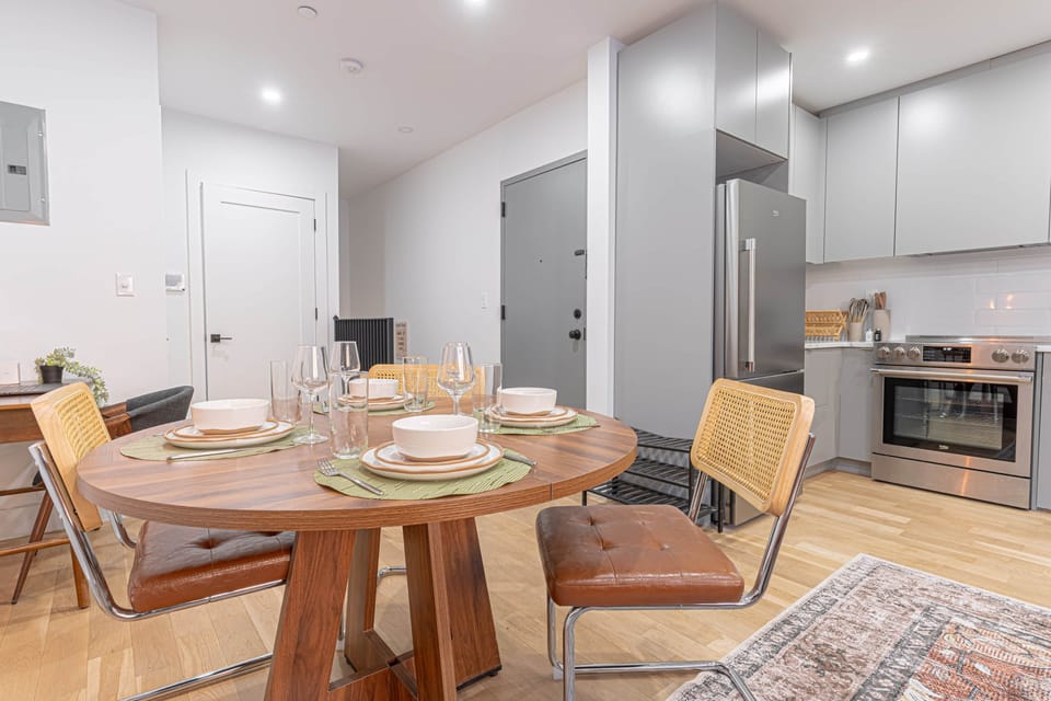 Dining table for 4 beside a sleek kitchen w/ stainless appliances—great for meals.