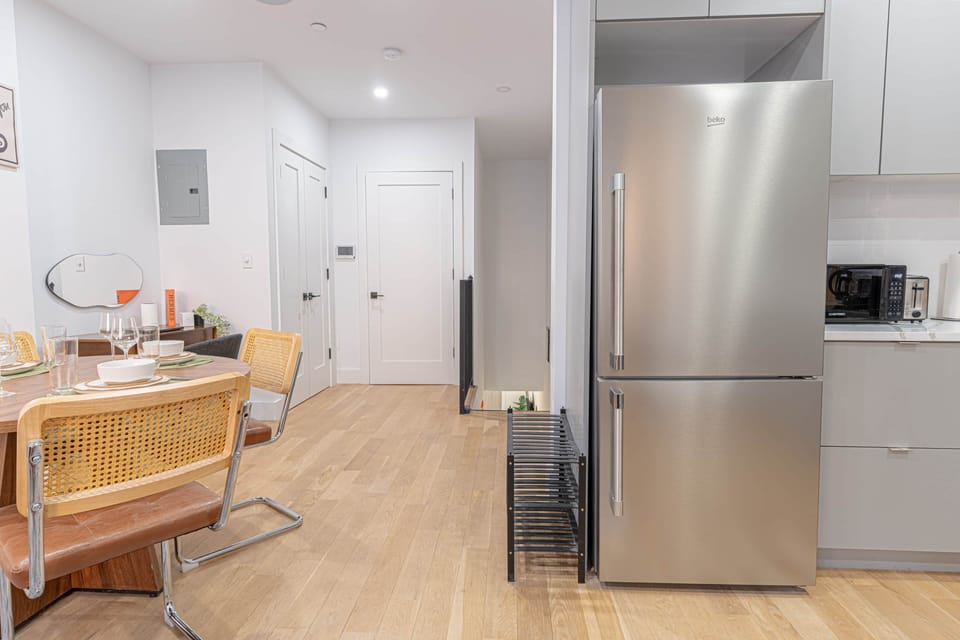 Modern kitchen/dining w/ full-size stainless fridge & table set for meals.