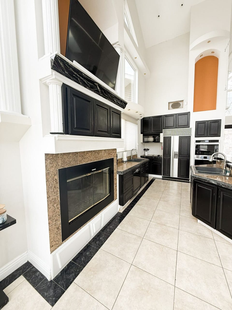 Gourmet kitchen with sleek black cabinetry, granite countertops, fireplace, and high ceilings for a luxury lakefront experience.