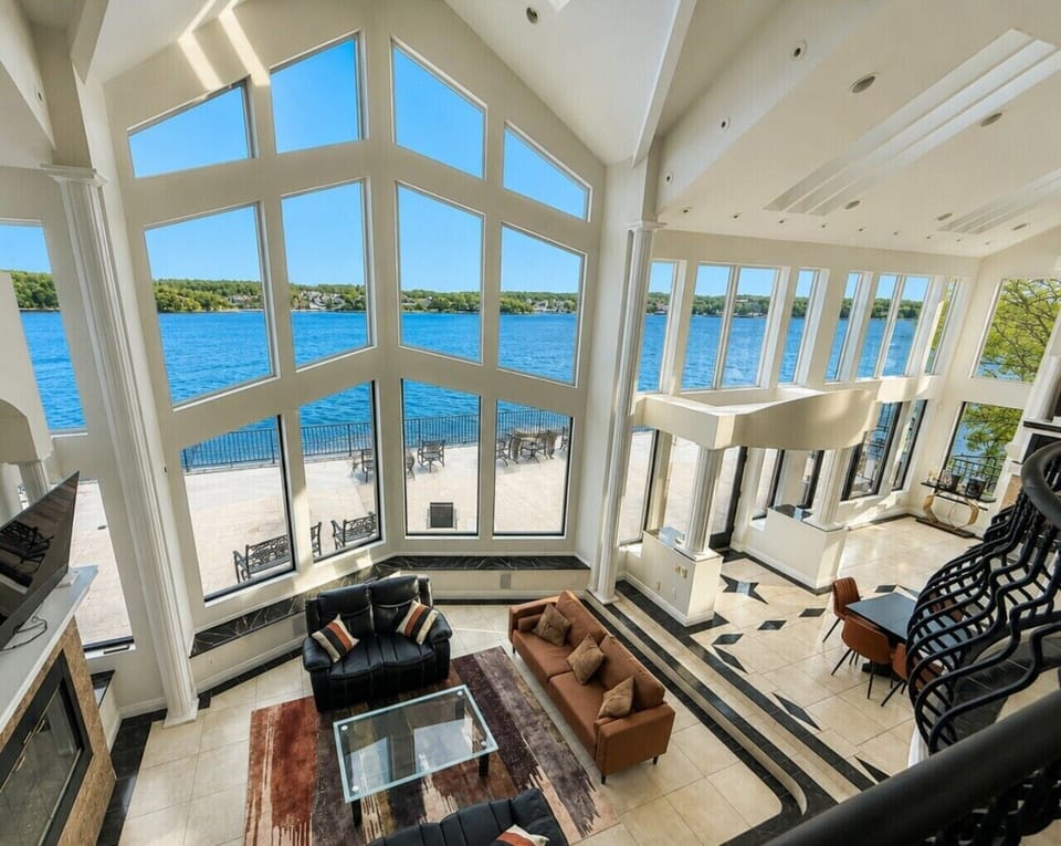 Luxury lakefront retreat with soaring floor-to-ceiling windows, breathtaking panoramic water views, elegant open-concept living, and upscale amenities