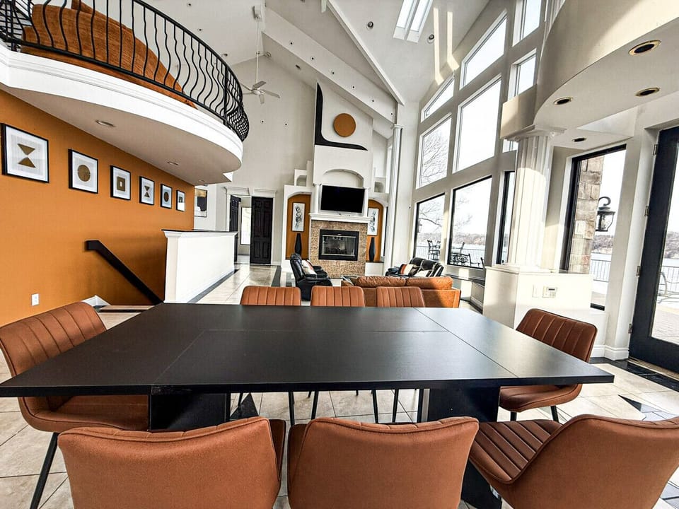 Modern open-concept dining and living area with lakefront views, high ceilings, and elegant contemporary design.