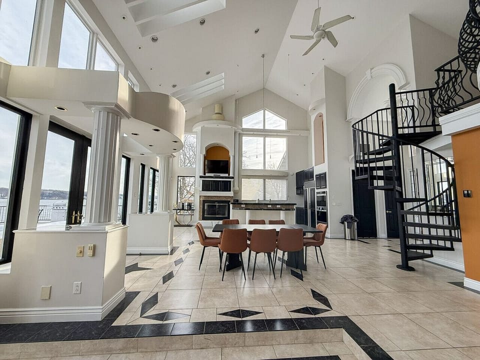 Stunning luxury lakefront home featuring soaring ceilings, wall-to-wall windows, a gourmet open kitchen, spiral staircase, and expansive entertaining space