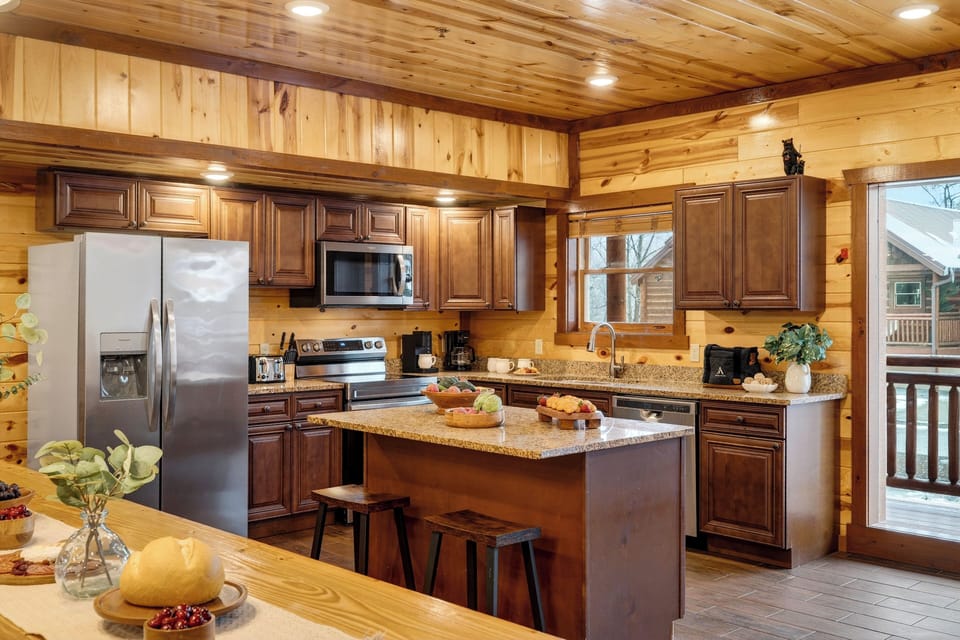 Fully equipped cabin kitchen with granite countertops, stainless steel appliances, and a central island—ideal for cooking, gathering, and shared meals.