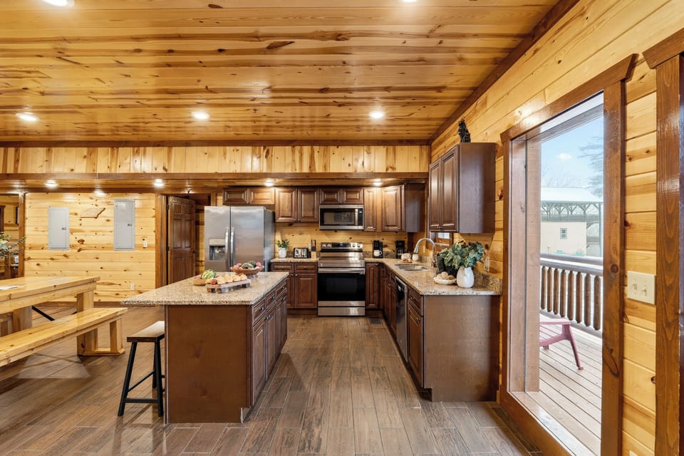Fully equipped cabin kitchen with granite countertops, stainless steel appliances, and a central island—ideal for cooking, gathering, and shared meals.