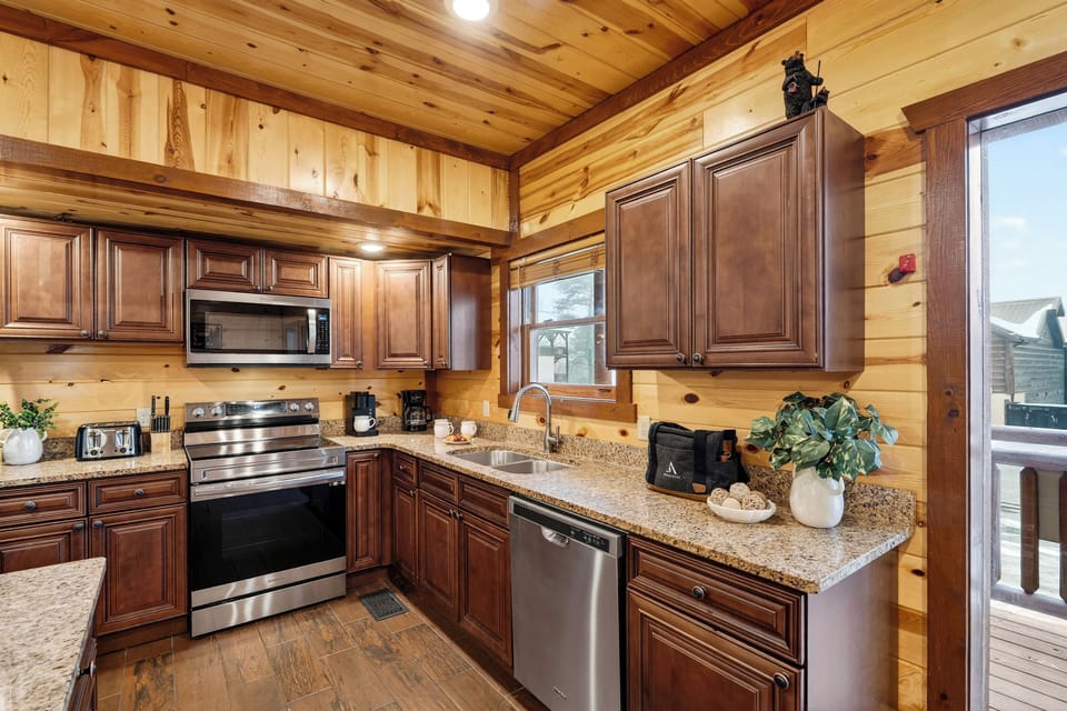 Fully equipped cabin kitchen with granite countertops, stainless steel appliances, and a central island—ideal for cooking, gathering, and shared meals.