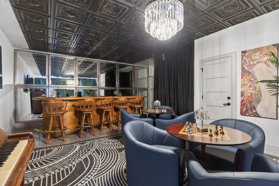 Stylish lounge with custom bar, plush seating, and statement chandelier. (The Great Gatsby)