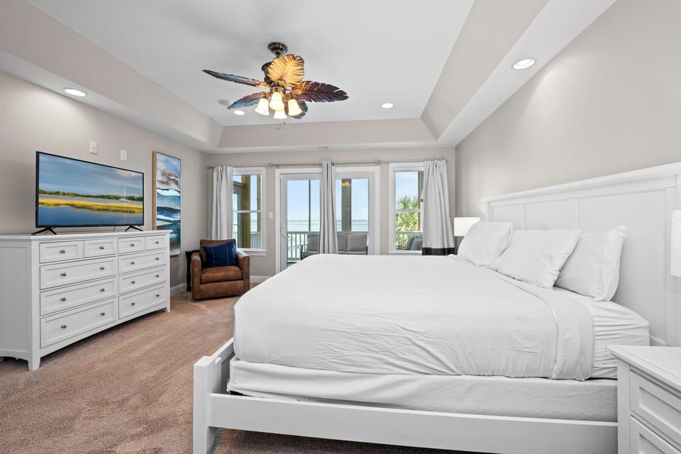 Wake to soft coastal breezes and stunning waterfront views from this serene bedroom. Crisp linens, tropical ceiling fan, and balcony access create your perfect seaside escape.