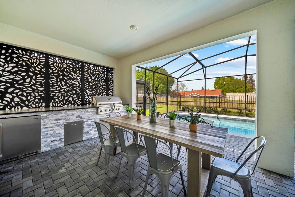 Enjoy a spacious outdoor dining area featuring an elegant wooden table and sleek metal chairs, ideal for gatherings. A striking decorative screen enhances the ambiance and provides a lovely view of the inviting pool.