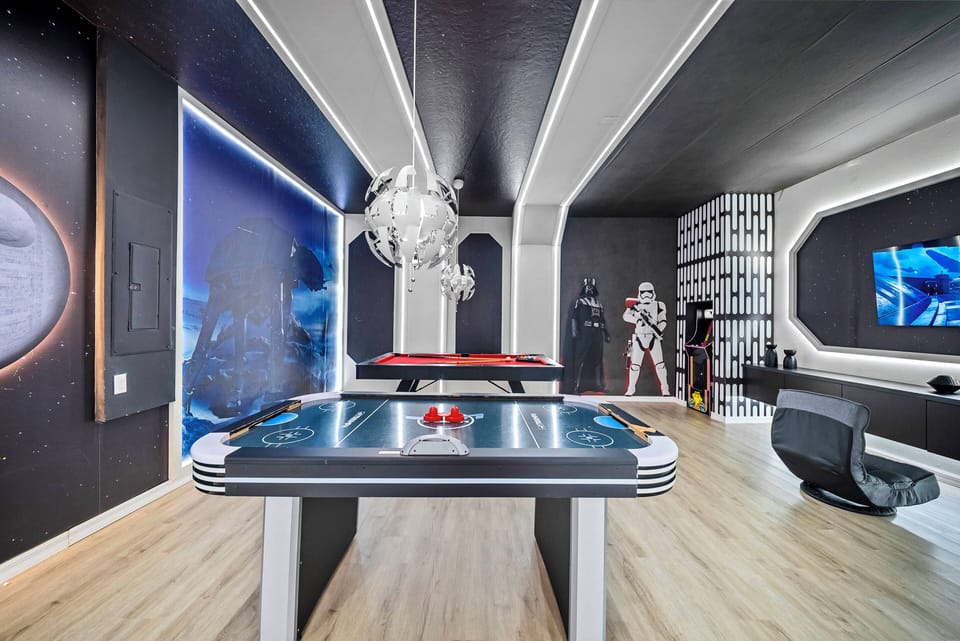Experience a captivating game room with sleek, futuristic décor, where a vibrant pool table and air hockey surface invite friendly competition, all enhanced by striking lighting and themed wall art for unforgettable fun.