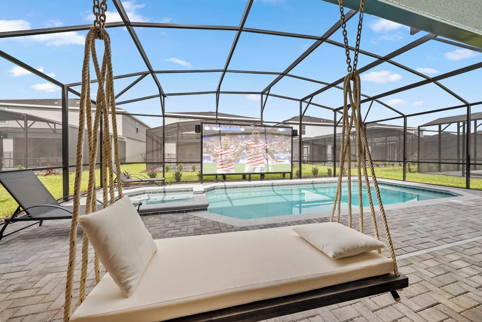 Relax on the chic swing chair overlooking the sparkling pool, where the outdoor space is perfect for sunny days and cozy evenings. The large screen invites movie nights under the stars, creating a unique entertainment experience.