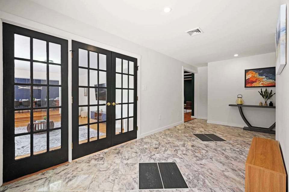 Elegant transition hallway with marble tile and French doors leading to the deck