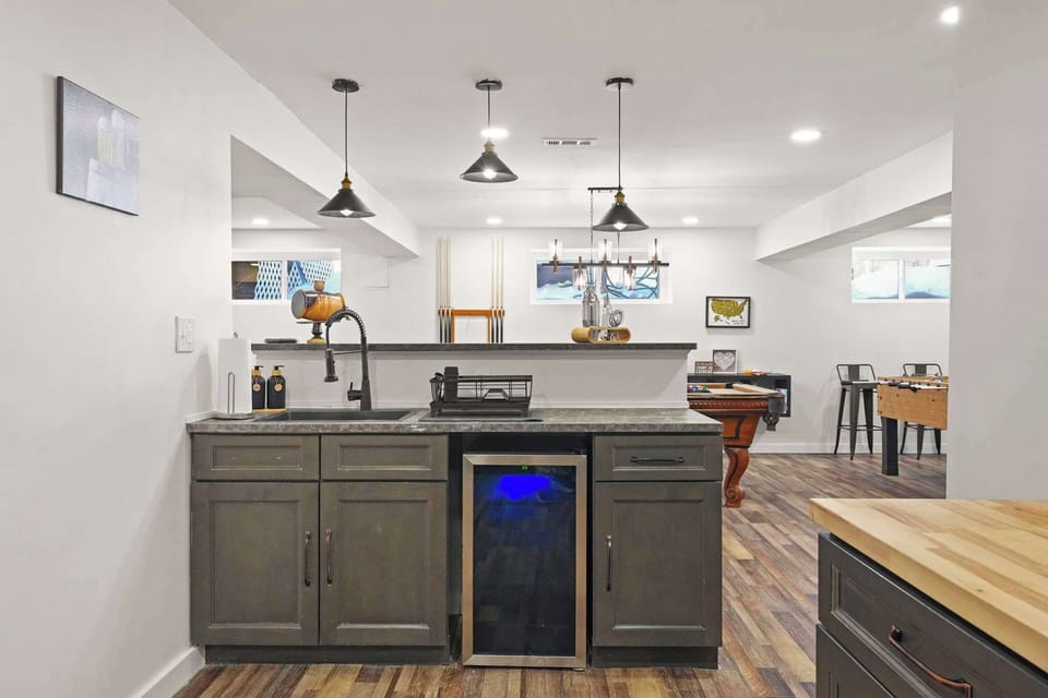 Stylish wet bar with wine fridge, pendant lights, and butcher block countertop