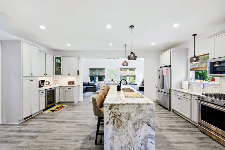 Kitchen - A marble waterfall island with bar seating anchors the bright, open chef's kitchen.