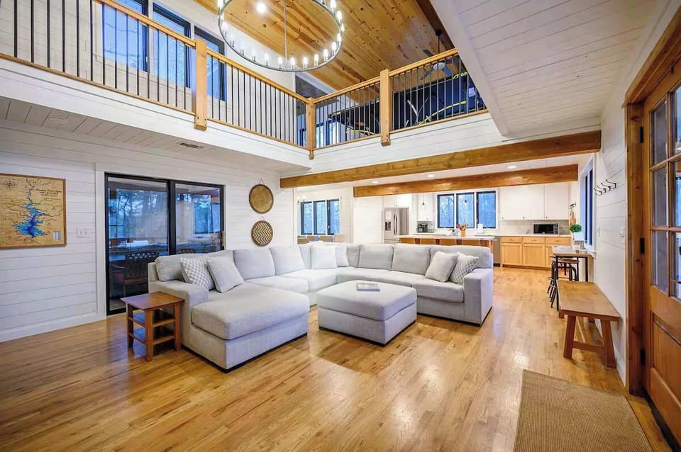 Bright, open-concept living space with soaring ceilings, cozy seating, and warm modern cabin style.
