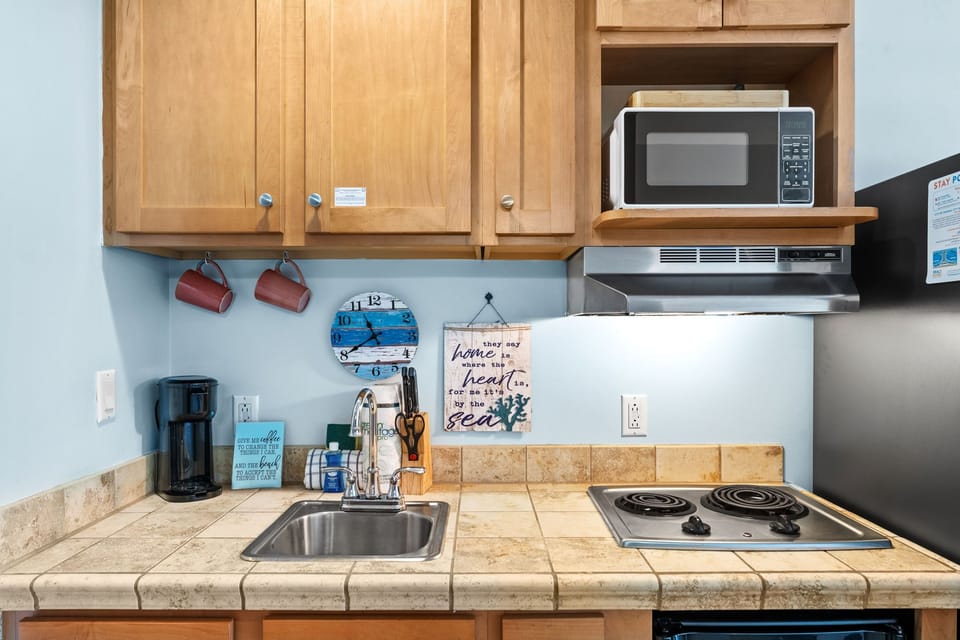 Your fully equipped kitchen awaits with everything needed to prepare meals, featuring tile counters, stainless appliances, and charming coastal touches.